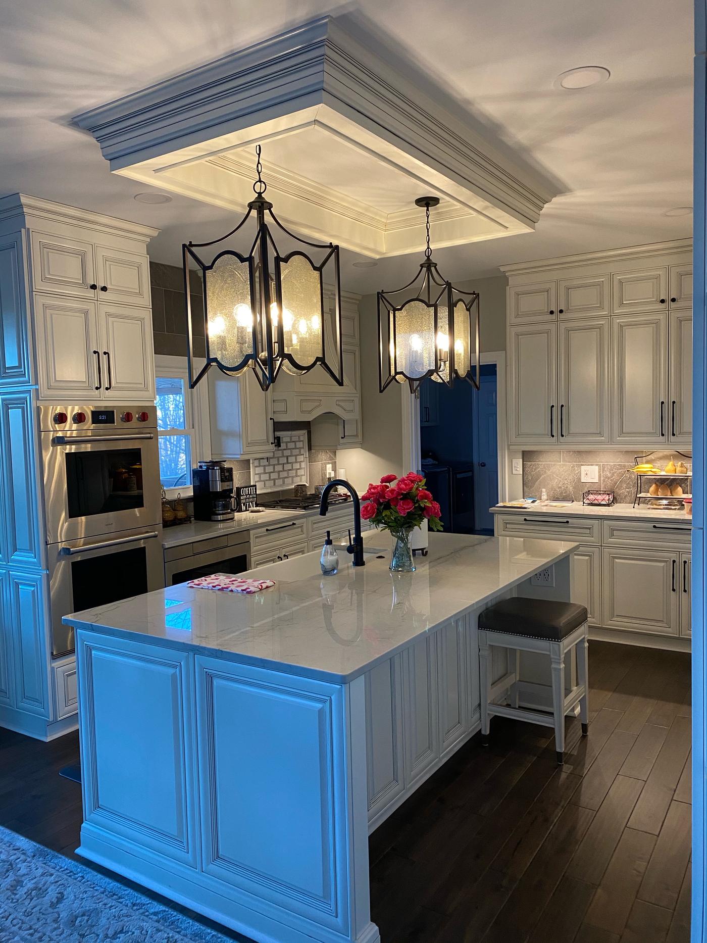 White kitchen with a quartz island and lantern pendants