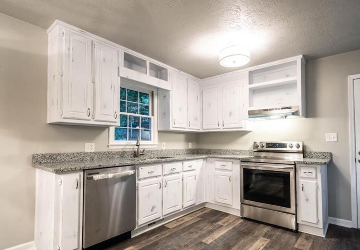 The same kitchen after: white cabinets, granite counters, stainless appliances and new flooring