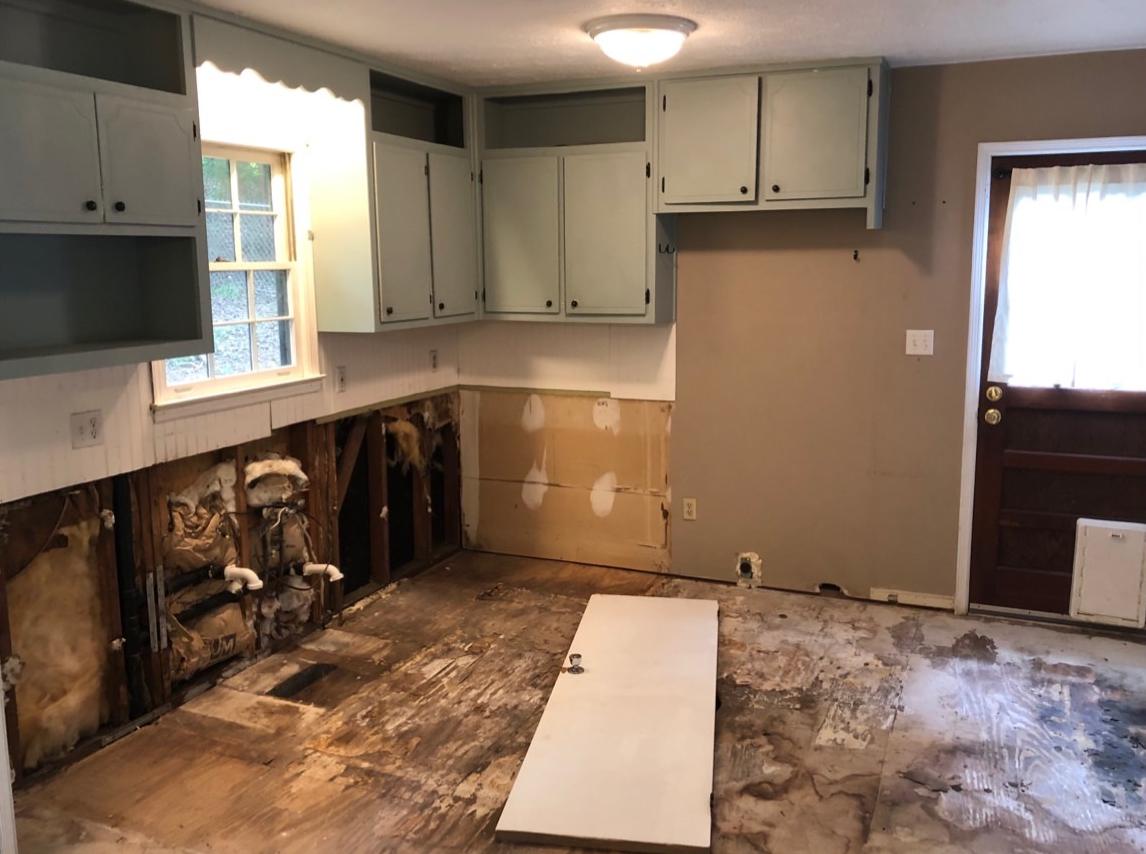 Kitchen before: torn-out cabinets, open walls and damaged subfloor